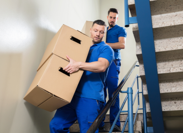 Military movers moving boxes down flight of stairs